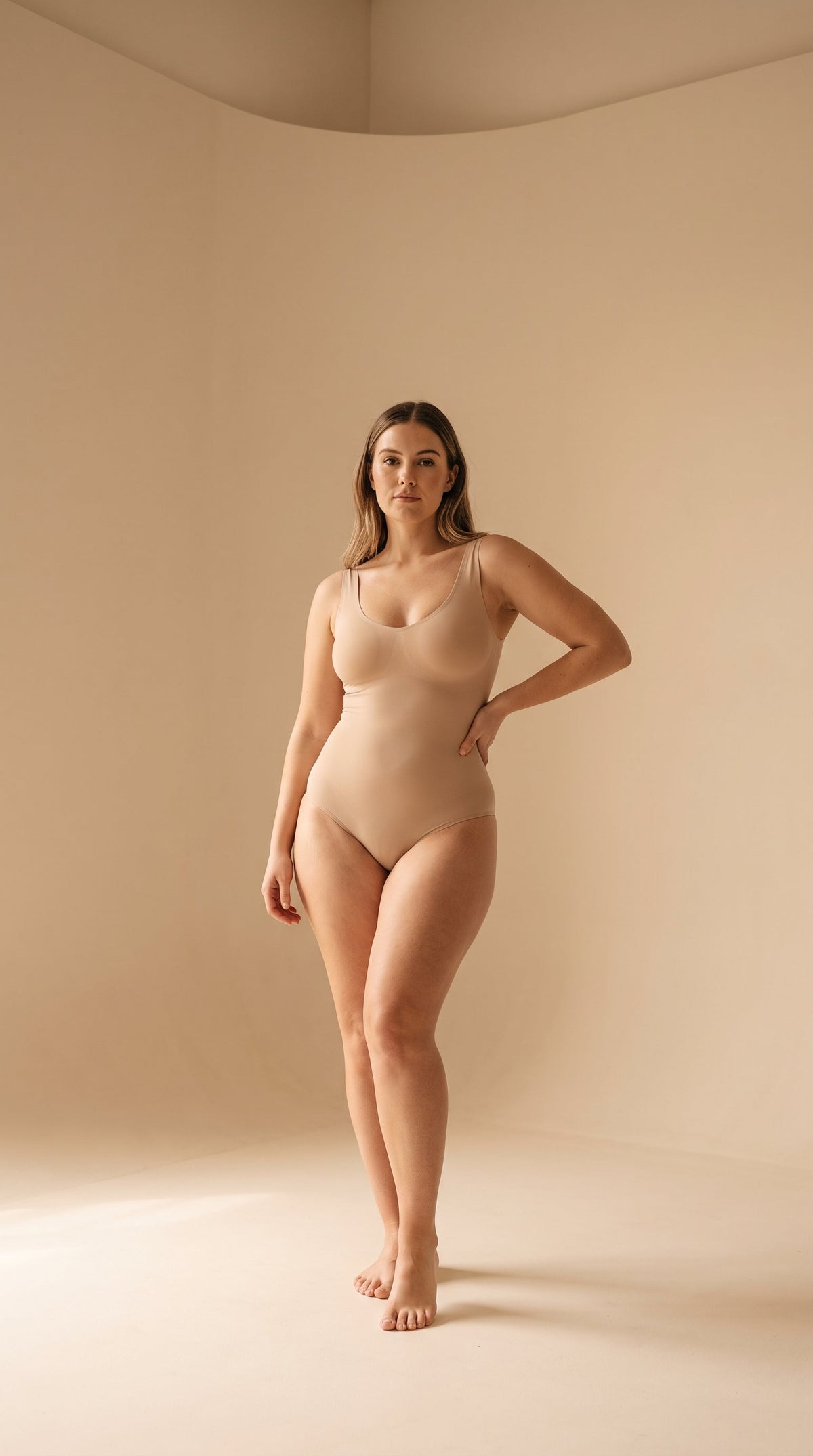 A model standing in a smooth nude shapewear bodysuit
